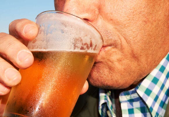 Man drinking a refreshing beer by the beach after a long hot walk