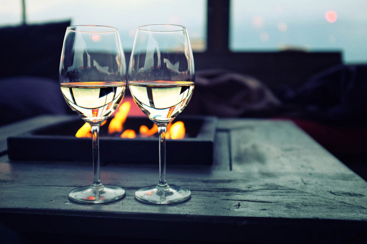 Two glasses of wine by a fire